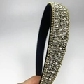 Detail view of a luxury rhinestone headband with sparkling diamonds on black fabric - White