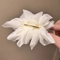 Detail of white chiffon flower hair clip with golden metal fastener held by hand - Off White