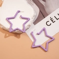 Macro di grandi orecchini a stella viola opaco su marmo e sfondo di rivista alla moda - Viola