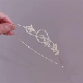 Detailed close-up of golden metal headband featuring rhinestone treble clef and floral patterns - Butterfly