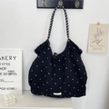 Close-up of black quilted floral tote bag with branded label and textured strap detail - Chiffon Small Floral Black