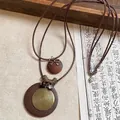 Gros plan sur un collier ethnique avec disques en bois et pendentifs spirale en bronze - Style Disque en Bois Marron (HN9383)