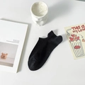 Solid black low-cut cotton blend boat sock with heel tab on a clean white desk background - One Size / Black