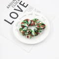 Detail of Christmas tree pattern fabric scrunchie on a white plate over a magazine - Red Green Christmas Tree Pattern