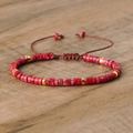 Handwoven imperial stone bracelet with red disk beads and golden accents on wood surface - No.47 Red Imperial Stone