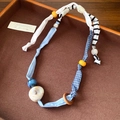 Detail van handgemaakte stoffen harthalsketting met streepjespatroon en gekleurde kralen - Blauw en Wit Gestreepte Houten Ring Stijl