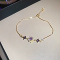 Macro shot of gold adjustable bracelet with purple gemstones and shimmering zircons - Purple Flower / Gold