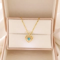 Detail of gold heart pendant with blue gemstone and zircon inlay in a jewelry box - Gold Sapphire Heart (A-501)