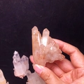 Natural white and orange crystal cluster specimen held against a black background - Approx. 50-100g