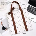 White quilted tote bag with brown heart prints and shoulder straps on a desk - Coffee Heart
