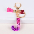 Letter J resin keychain with pink tassel and red glitter heart on white pedestal - Letter J