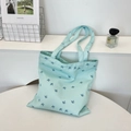 Detail of light blue canvas tote bag with dark blue bird prints in a lifestyle setting - Shoulder Style