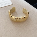 Dettaglio del bracciale a polsino dorato con trama in metallo liquido su tessuto beige - Stile Pieghettato a Onde Irregolari Oro (10#)