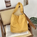 Vista dettagliata della borsa tote in tela giallo zenzero su una sedia in rattan vintage - Giallo