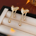 Detailed view of polished gold lava heart earrings with fluid metallic texture in a gift box - Silver Pin / Gold