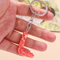 Close-up of letter L resin keychain with vibrant red sequins and silver metal ring - Letter L
