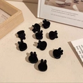 Detail view of ten mini black velvet rabbit ear hair clips on a cozy desktop surface - Black Flocked Rabbit