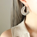 Boucle d'oreille épaisse en U argentée en acier inoxydable portée par un mannequin - Couleur Acier