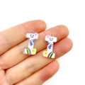 Close-up of small white acrylic charms with colorful rainbow and smiley patterns for DIY - Letter I