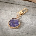 Detail of purple dried flower resin keychain with irregular gold metal plating edge - Violet