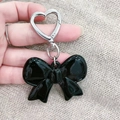 Elegante portachiavi con fiocco in acrilico nero e gancio a cuore su sfondo lavorato a maglia - Stile Fiocco Nero Verticale (M322竖版黑蝴蝶结)