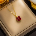 Gouden klavertje vier ketting met rode hartvormige stenen op een sieradendoosje - Rode Strass