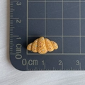Macro view of a miniature resin croissant with colorful sprinkles on a scale mat - 08*Brown Spiral Bread