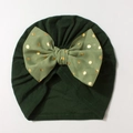 Close-up of baby turban hat in dark green featuring a large gold polka dot bow - Dark Green