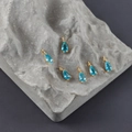 Macro detail of six 18k gold plated water drop pendants with blue zircon on grey rock - Light Blue Water Drop Style (M108904)