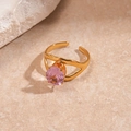 Macro detail of golden irregular wave ring featuring a four-prong set pink zircon stone - Gold Geometric