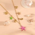 Detailansicht der goldenen Meeresanhänger mit Seestern und Muscheln auf Pfirsich - Rosa Halskette