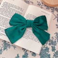 French vintage dark green satin bow hair clip placed on a book for elegant hair styling - Hair Bow / Green