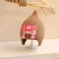 Detailed view of brown knit baby hat with pink plush doll braids and warm ear flaps - One Size (Toddler) / Khaki
