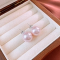 Close-up of pink round pearl stud earrings with silver pins on a vintage jewelry box - Pink Pearl Studs (14mm)