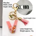 Detail of pink resin letter V keychain with gold bee pendant and leather tassel - Letter V Bee Keychain