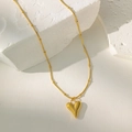 Detailed view of a gold heart pendant necklace with pearl on a white stone background - Bead Chain Heart Necklace / Gold