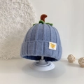 Detail der Baby-Strickmütze in Blau mit Kürbisblättern und einem kleinen Baby-Etikett - Blau