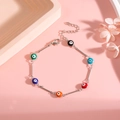 Detailed shot of silver evil eye bracelet with colorful enamel beads on a pink background - Silver Bracelet