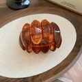 Close-up of wide stretch bracelet with oval amber acrylic tiles and tortoise patterns - Amber