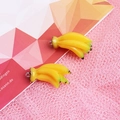 Detail shot of two yellow resin banana pendants on pink lace fabric for DIY crafts - with Hook / Banana