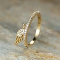 Macro shot of gold-plated ring with sparkling zircon pavé and hanging angel wing pendant - US 7 / Gold