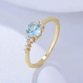 Anello in argento dorato con topazio azzurro e piccole gemme trasparenti su tessuto bianco - US 6 / Oro (KR1535)
