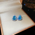 Macro shot of silver hulu earrings with blue zircon in a luxury jewelry display box - Silver-Blue