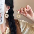 Dettaglio di orecchini a cerchio dorati intrecciati con perni in conchiglia bianca - Stile Retrò Intrecciato Tondo