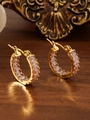 Détail macro de boucles d'oreilles créoles dorées 18k avec zircons roses sur fond de bois - ZHE2399 - Strass Rose / Or 18K