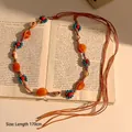 Détail de chaîne de taille bohème avec perles, conques et cordes sur un livre ancien - Style Tissé à Perles Minérales Colorées