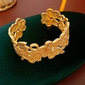 Détail d'un bracelet ouvert doré à motif floral et dentelle sur support en velours - Bracelet-Or (Plaqué Or Véritable)