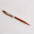 Top view of rose gold metal ballpoint pen filled with colorful crushed crystal stones - Morganite