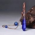 Macro shot of blue hexagonal stone pendant with vintage copper cap on rustic wood - Antique Bronze Lapis Lazuli