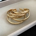 Close-up of stacked golden bracelets with hammered texture on a gray velvet tray - Hammered Model / Gold